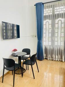 a table and chairs in a room with a blue curtain at SAM HOUSE 2 Huế in Cồn Giả Viên