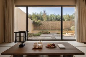 a room with a table with a bowl of fruit and a large window at PLAN B00b7ANADOL in Xianning