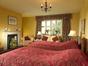 a bedroom with a red bed and a fireplace at Soulton Hall in Wem