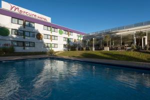 a hotel with a swimming pool in front of a building at Mercure Hotel Saarbrücken Süd in Saarbrücken