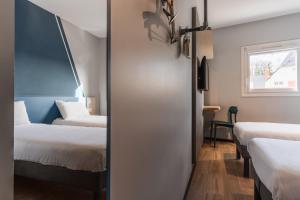 a small room with two beds and a window at Hotel Ibis Budget Fecamp in Fécamp