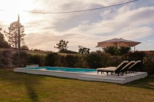 a pool with a table and chairs and an umbrella at Casa do Arrozal Comporta in Comporta +16 photos