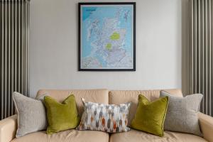 a couch with pillows and a map on the wall at West Highland Apartments Milngavie - The Nevis in Milngavie