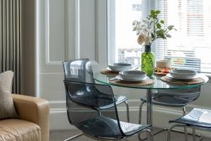 a dining room table with chairs and a vase of flowers at West Highland Apartments Milngavie - The Nevis in Milngavie