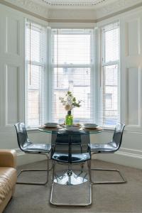 a dining room with a glass table and chairs at West Highland Apartments Milngavie - The Nevis in Milngavie