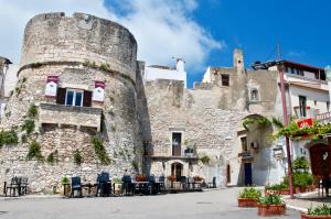 a large stone building with tables and chairs in front of it at Al Corso Charming Rooms in Peschici