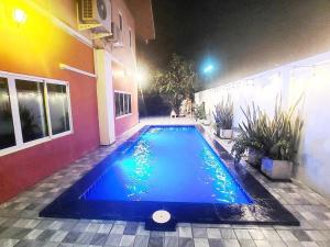 a swimming pool in front of a house at night at Baan Pink Pool Villa Pattaya in Ban Huai Yai