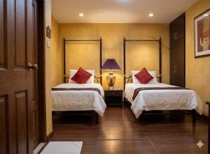 a hotel room with two beds with red pillows at Chaba silom in Bang Rak