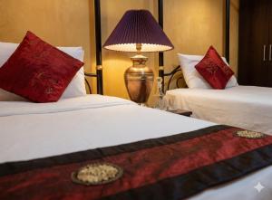 a hotel room with two beds and a lamp at Chaba silom in Bang Rak