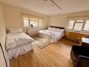a bedroom with two beds and two windows at Spacious House Sleeps 10 -Near BikePark Wales -Central -Parking in Troed-y-rhiw