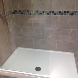 a shower with a glass door on top of a bathroom at Mill Cottage in Malpas