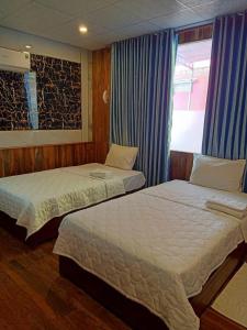 two beds in a hotel room with a window at Hotel View Sông Phú Quốc in Phú Quốc +2 photos