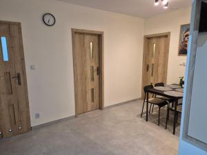 a room with two doors and a table and a clock at Apartament Pracowniczy in Mielec