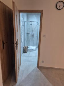 a bathroom with a shower and a clock on the wall at Apartament Pracowniczy in Mielec