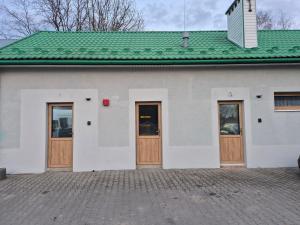 a white building with wooden doors and a green roof at Apartament Pracowniczy in Mielec