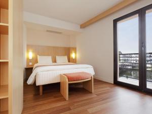 a bedroom with a bed and a large window at ibis Auxerre Centre in Auxerre