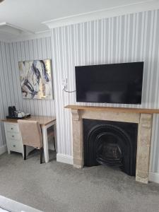 a living room with a fireplace with a television above it at The Abbey Town House in Cheltenham +30 photos