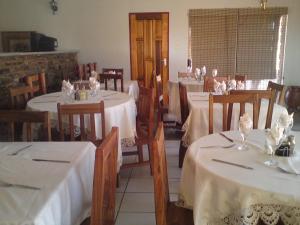 une salle à manger avec des tables et des nappes blanches dans l'établissement Murangi Travel Lodge, à Windhoek