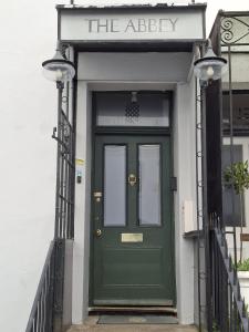 a green door with a sign that reads the abbey at The Abbey Town House in Cheltenham
