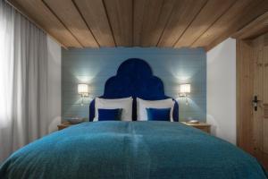 a bedroom with a blue headboard and a bed at Hotel La Perla: The Leading Hotels of the World in Corvara in Badia