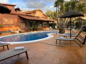 a pool with chairs and umbrellas next to a house at CARIBBEAN Home in Montcada i Reixac