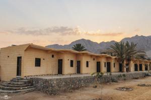 a building in the desert with mountains in the background at The Sea side camp nuweiba in Nuweiba
