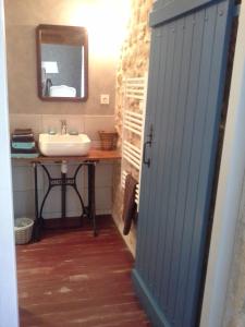 a bathroom with a sink and a mirror and a door at Le Logis Du Four in Soudan