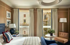 a bedroom with a bed and a chair and a window at Rocco Forte The Carlton in Milan +66 photos