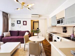 a living room with a purple couch and a table at Victoriei Boutique Apartment in Bucharest