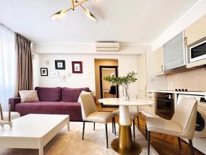 a living room with a purple couch and a table at Victoriei Boutique Apartment in Bucharest