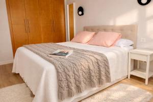 a bedroom with a white bed with pink pillows at Corazón de la Ciudad by apartamentoscatedralcamino in Burgos