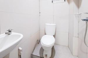a white bathroom with a toilet and a sink at SANS Stay Raja Soeta Hostel Lampung in Hajimana +22 photos