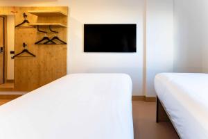 a bedroom with two beds and a tv at easyHotel Alicante Centro in Alicante