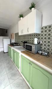 a kitchen with green cabinets and a microwave at Little apartment in Hammamet
