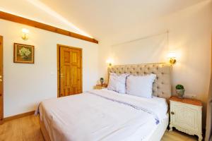 a bedroom with a large bed with white sheets at Villa Sofayla w Jacuzzi near the Pirin Golf Resort in Bansko