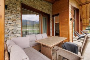 a patio with a couch and a wooden table at Villa Sofayla w Jacuzzi near the Pirin Golf Resort in Bansko