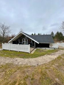 a house with a white fence in front of it at Glamping Cabin Wilderness bathing and relaxation in Silkeborg