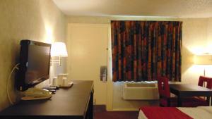 a hotel room with a desk with a television and a bed at Oceanside Lodge in Marmora