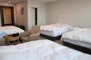 a room with three beds and a table and chairs at Ocean Hotel Pohang in Pohang