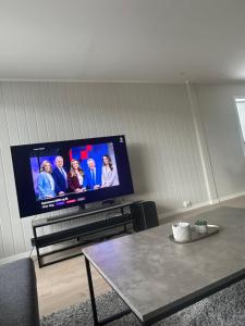 a living room with a flat screen tv and a table at Gullvikvegen 33 in Namsos +3 photos