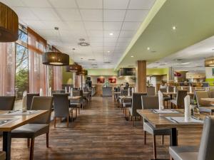a dining room with wooden tables and chairs at Mercure Hotel Hamburg am Volkspark in Hamburg