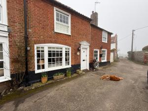 a dog laying on the ground in front of a brick house at York Cottage in Southwold