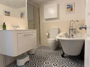 a bathroom with a tub and a toilet and a sink at York Cottage in Southwold +31 photos