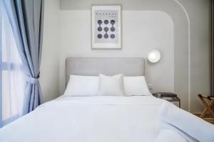 a bed with white sheets and pillows next to a window at Piccadilly Service Residence Greentown Ipoh in Ipoh