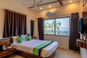 a bedroom with a bed and a large window at Kaizen Stays And Resto in Panchgani +19 photos