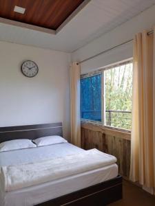 a bedroom with a bed and a window with a clock at Ribhoi Jungle in Khānāpāra