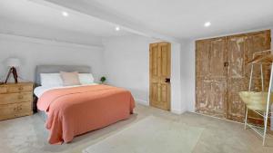 a bedroom with an orange bed and a wooden door at Vine Cottage in Thornham