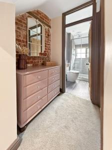 a bathroom with a pink dresser and a mirror at Vine Cottage in Thornham +5 photos