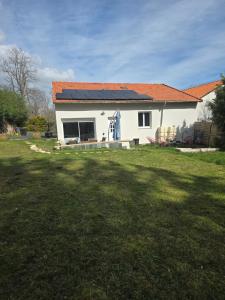 a white house with a solar roof and a yard at Le Little cocoon in Durtol