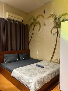 a bedroom with a bed and palm trees on the wall at H2T Home in Ho Chi Minh City